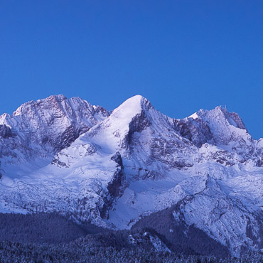 Buckelwiesen im Winter mit Schnee. Blick auf Wetterstein, Hochblassen, Alpspitze und Zugspitze zur blauen Stunde.
